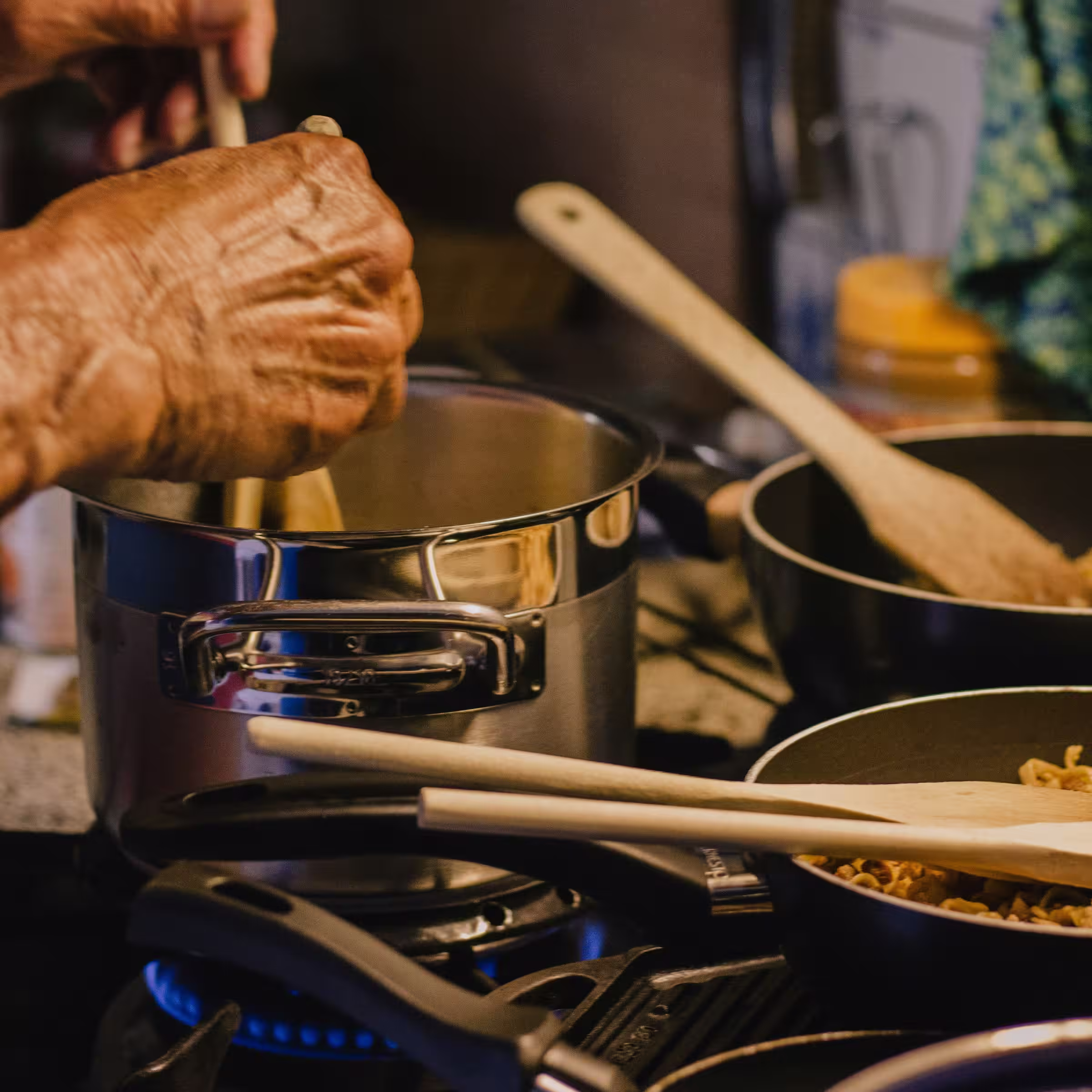 A grandmother in a kitchen, stirring a pot of stew over a lit stove with other enticing dishes cooking nearby